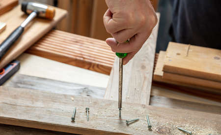 Screwdriver manual tool, male hand screw on wood.  Carpenter work bench table closeup view. DIY, home repair and fix.の写真素材