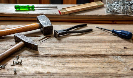 Work tool old used, hammer, sledgehammer plincers and nail on wood, carpenter workshop bench table,...
