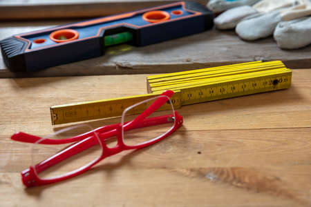DIY, home repair and fix. Tool and red eyeglasses on wood, Workshop wooden bench closeup viewの写真素材