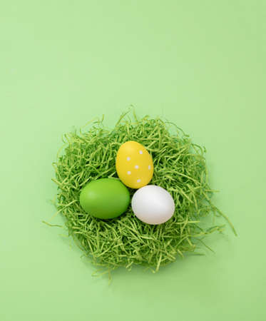 Easter eggs in a nest, pastel green background, top view. Spring Holiday celebration, copy space.の写真素材