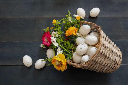 Easter Holiday. Quail egg in a wicker basket, blue wooden table background, top view. Spring flower...