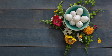 Happy Easter. Quail egg in a ceramic bowl and Spring flower decoration, blue wooden table...
