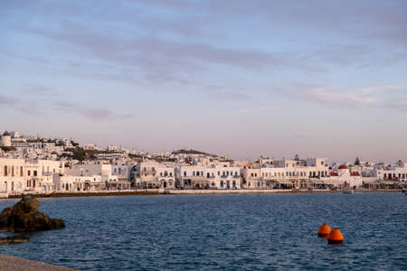 Greece, Mikonos island, Cyclades. Mykonos Chora, waterfront white traditional building, shop, sea, blue sky background. Summer cosmopolitan destination for vacation.の写真素材
