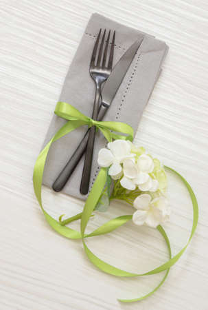 Spring holiday table setting. Elegant cutlery, grey cloth napkin and flower decoration on white wood, wedding celebration menu, top viewの写真素材