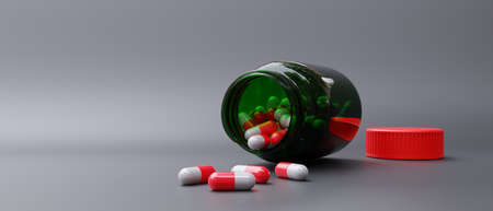 Capsule scattered out of green bottle on grey background. Medicine pill, drug dose and glass...