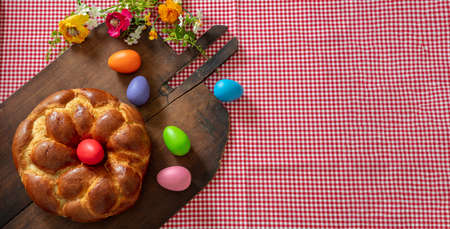 Easter Greek tsoureki braid top view. Sweet bread brioche and colorful egg on old rustic wooden...