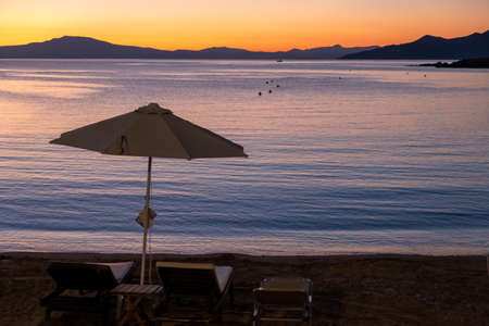 Wicker umbrella and sunbed at Stoupa sandy beach at sunset. Mani Messenia, Greece Peloponnese. Summer vacation destinationの写真素材