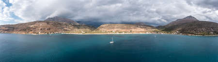 Greece, Peloponnese. Laconia Mani bay, coastline, seaside fishing village under heavy cloud sky, aerial panoramic viewの写真素材