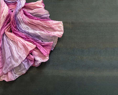 Pastel colorful cloth on empty blue brown wooden board background. Luxury bright rainbow color textile, wavy material decorative on dark grunge surface. Overhead view, copy space.の写真素材