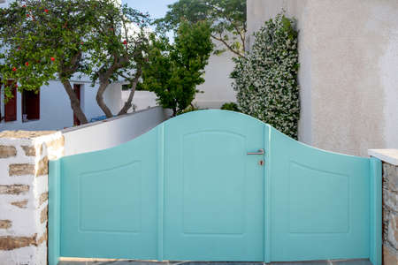 Greek Island, Cyclades. Light blue wooden retro yard entrance, view of blooming plant and fruit tree...