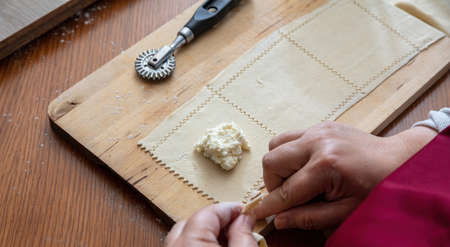 Female hands making pastry, homemade dough stuff with mild cheese and egg, close up above view. Kalitsounia Cretan traditional pies preparation.の写真素材