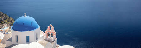 Santorini, Greece. Panorama of Greek Orthodox Church with blue dome and blue calm sea in Oia village caldera, aerial view. Copy space, card templateの写真素材
