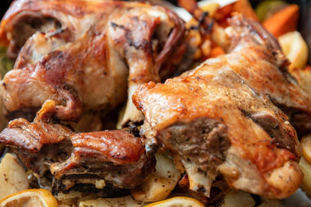 Lamb leg with bone baked with potato and herb in oven. Traditional Greek Easter food, marinated goat or sheep meat cooked with fresh vegetable. Close up view.の写真素材