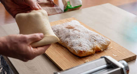 Pasta maker machine. Fresh pasta homemade preparation. Male hand making dough phylo close up view