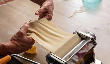 Dough homemade preparation. Fresh pasta maker machine. Male hand making dough phylo for pies and...