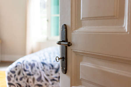 Door open, blur elegant hotel room or house bedroom interior, window and bed. Retro door knob on...
