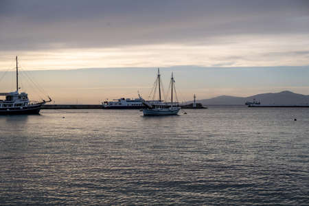 Cyclades, Greece. Moored boat at Mykonos island harbor, rippled sea, sky in the evening background.