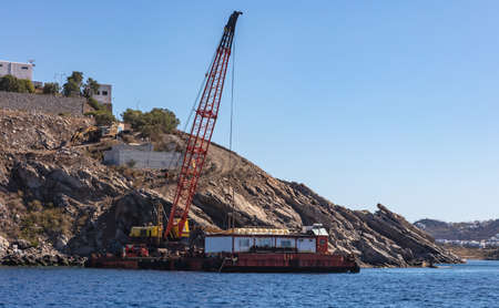 Marine works near Mykonos island port. Cyclades Greece. Construction machine, crane and barge on...