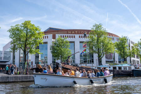 Amsterdam, Netherlands May 22, 2022. Tourists enjoy sightseeing on canal cruise boat in front of...