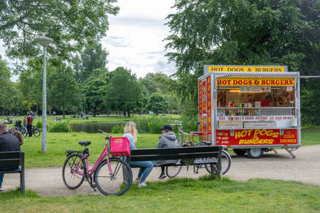 Amsterdam, Netherlands May 21, 2022. Fast food from truck next to lake, street kitchen at public Holland park. Modern wagon canteen. People enjoy the natureのeditorial素材