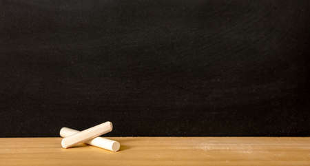 School chalkboard, blank empty black board and white chalk piece on wooden frame sill, copy spaceの写真素材