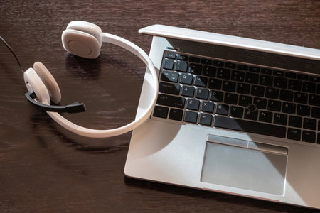 Call center, home office, customer support, help desk. Headset on a laptop, wooden table, view from...
