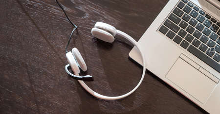 Headset on a laptop, wooden table, view from above, copy space, Call center, home office, customer support, help deskの写真素材