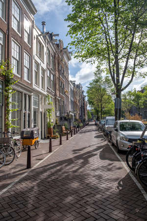 Amsterdam city paved sidewalk. Traditional red brick wall houses, bicycles parked in front of the buildings, Residential neighborhood, Holland Netherlands.の写真素材