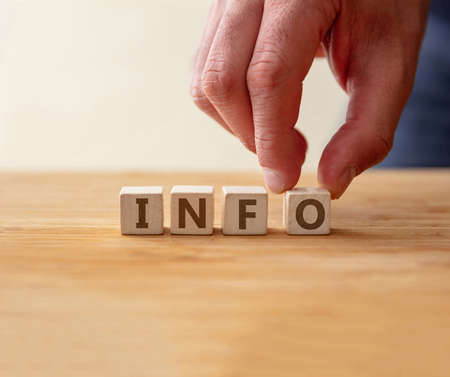 Info concept. Word info on wooden cube with finger to touches letter o. Information, advised message...