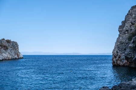 Greece. Blue rippled sea between huge rocks, blue sky background. Summer destination Mani Laconia, Peloponnese crystal clear water.の写真素材