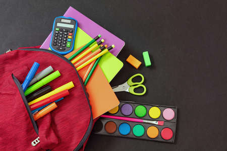 Back to school. School supplies and a red student backpack isolated on black color background, top view, copy space.の写真素材