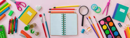 Back to school background. Open notebook on pink color office supplies and stationery flat lay, top view. Blank empty paper, copy spaceの写真素材