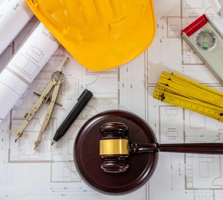 Construction and Labor law flat lay. Yellow safety helmet and judge gavel on building blueprint plans, top view.の写真素材