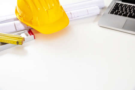Construction project, Architect engineer office. Safety helmet, building blueprint plans and laptop...