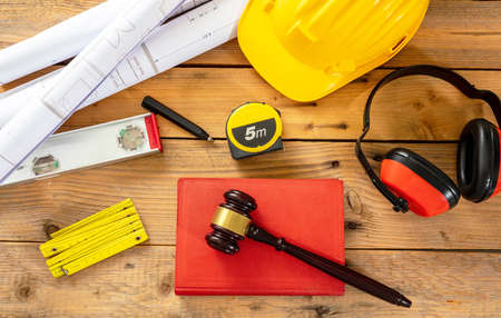 Construction and Labor law flat lay. Judge gavel and engineering tools on wooden table, top view.
