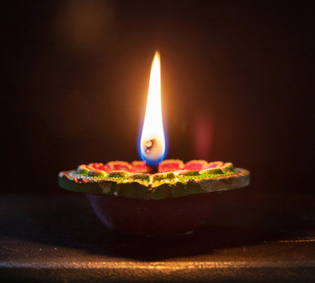 Deepavali Diwali. Hindu festival of lights. Clay diya candle. Oil lamp lit on dark background, copy space.の写真素材