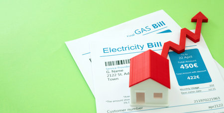 Home electricity heating and water cost increase. Domestic utilities rising price. House model, bills and red arrow up.の写真素材
