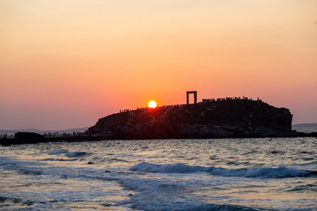 Naxos island, sunset over Temple of Apollo, Cyclades destination Greece. Tourists admire the sundown from the islet of Palatia. Ripple sea colorful sky background.のeditorial素材