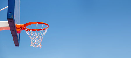Basketball hoop, red ring and net on backboard, clear blue sky background, copy space. Sunny day, outdoors sport courtの写真素材