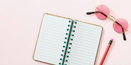 Open diary blank paper, pencil, sunglasses on pink background. Blank spiral notepad, copy space, top viewの写真素材