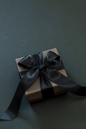 Gift box with black ribbon isolated on black, copy space. Black Friday Sale and Christmas presents