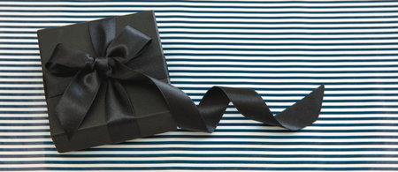 Gift box wrapped with luxury black satin ribbon on striped background, top view. Black Friday Saleの写真素材