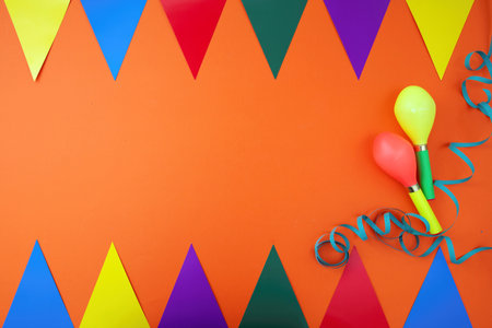 Carnival party, garland, colorful triangle flag as frame, maraca, serpentine on orange background. Invitation card. Space for text, ad template.の写真素材