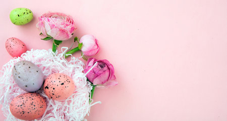 Easter eggs nest and Buttercups flower bouquet on pastel pink background, copy space. Happy Easter