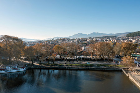 Giannena city Pamvotis Lake, Epirus Greece. Ioannina town lakefront, moored boat, outdoors cafe under tree, blue sky background. Above viewの写真素材