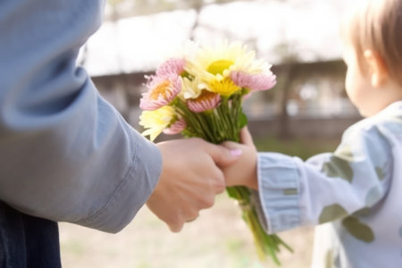 Little boy giving flower bouquet to his mother outdoors, closeupの素材