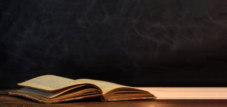 Vintage book on black blank chalkboard background, texture. Leather hardcover old open book on...
