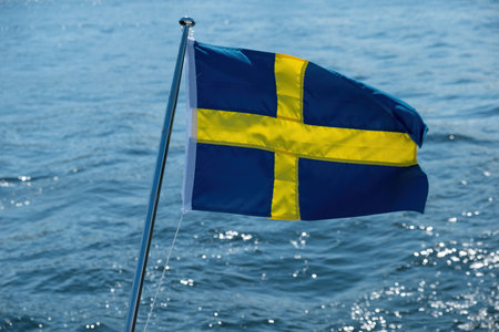 Sweden national flag waving on boat flagpole, blur sea water background, sunny day,の写真素材
