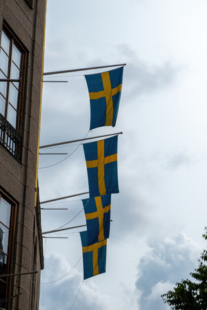 Sweden national flags waving on a Stockholm city building facade, cloudy sky backgroundの写真素材