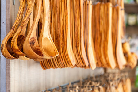 Handmade kitchen utensil, handicraft wooden cutlery hanging outdoors of souvenir store on blur background. Greek traditional souvenir saleの写真素材